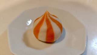茹で上がった蟹子包を1粒、白い皿にのせたところ。オレンジと白のシマシマがつやつやしている