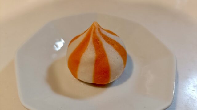 茹で上がった蟹子包を1粒、白い皿にのせたところ。オレンジと白のシマシマがつやつやしている