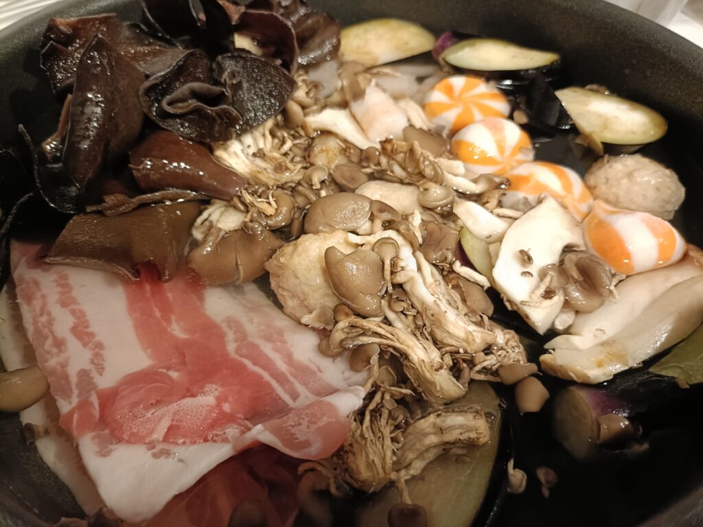 鍋に豚バラ肉・キクラゲ・まいたけ・ナス・サーカス団子・肉団子を入れて水を注いだところ